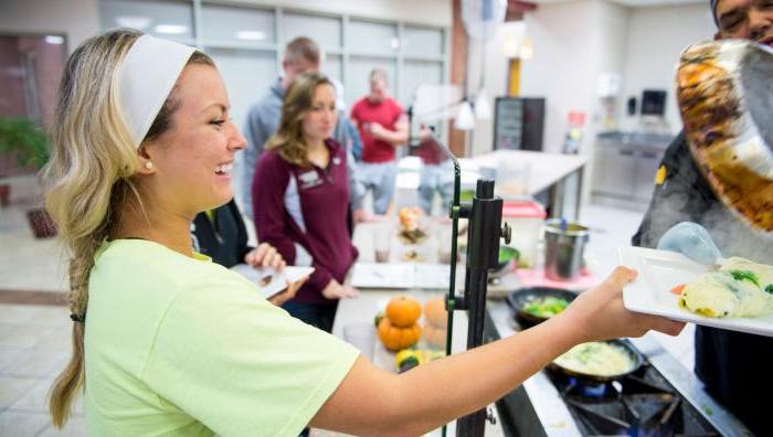 A young female student is being handed an omelette at a dining station at Springfield College